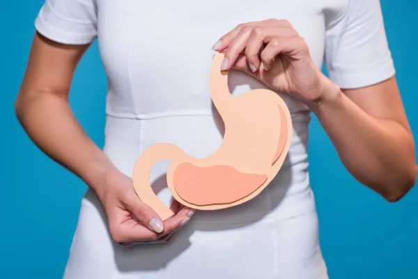 Person hält ein schematisches Magenmodell vor dem Bauch – Symbol für Verdauung und Darmgesundheit