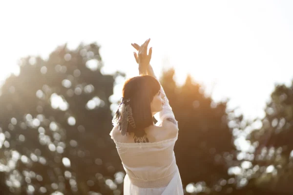Person streckt die Arme im Sonnenlicht und genießt einen ruhigen Moment im Freien